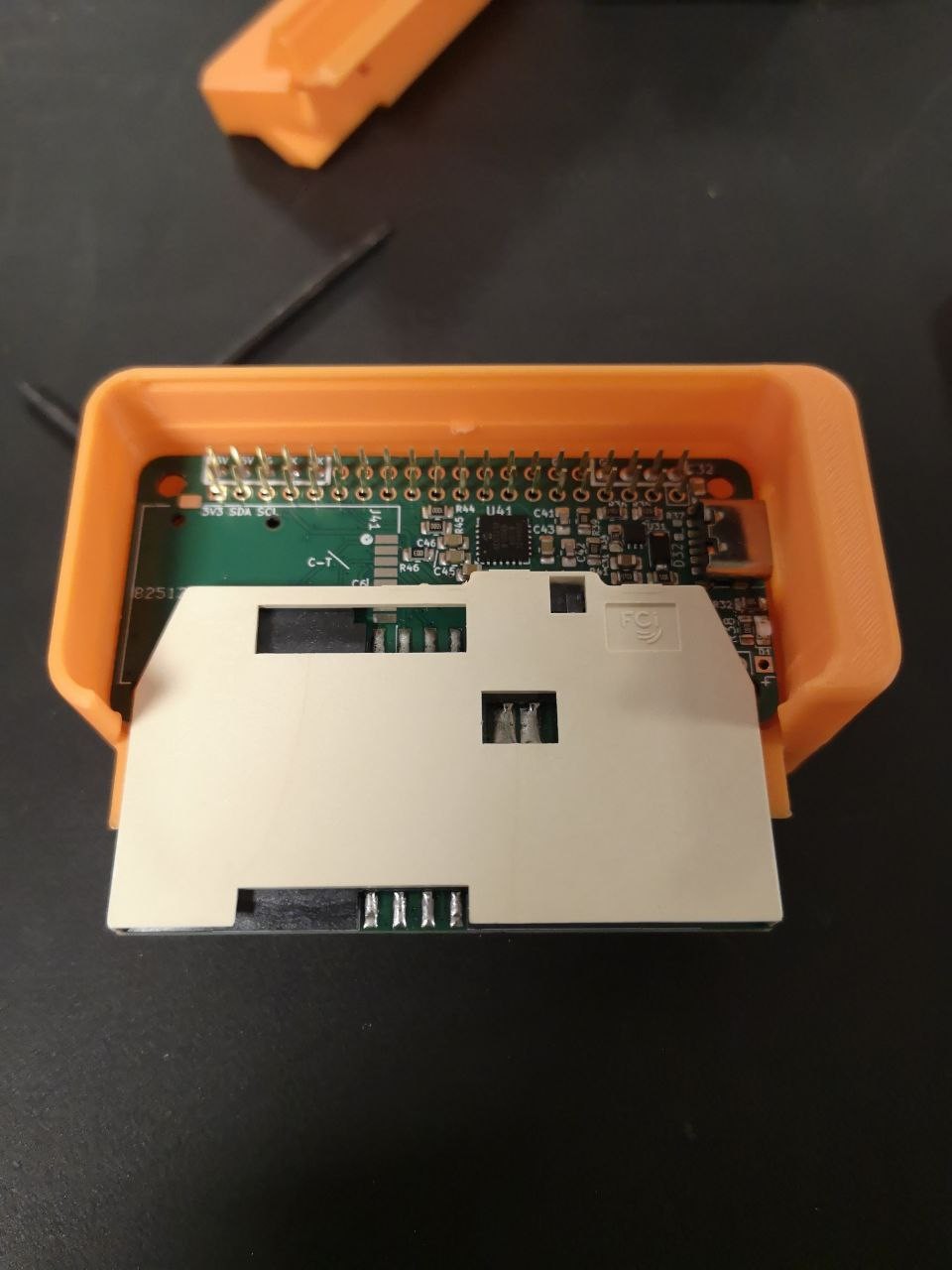 An open orange 3D-printed enclosure showing the custom smartcard reader board stacked on a Raspberry Pi Zero.