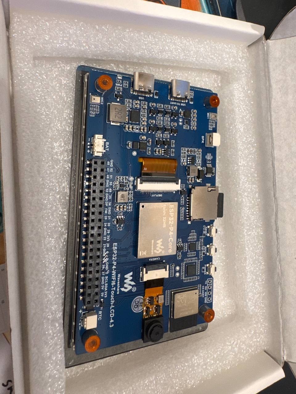 Rear view of the blue Waveshare ESP32-P4 touchscreen development board, showing its chips, connectors and printed labels.